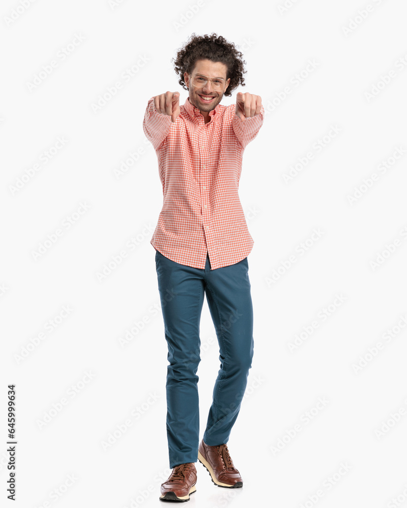 happy young man with glasses pointing fingers forward and smiling happy young man with glasses pointing fingers forward and smiling