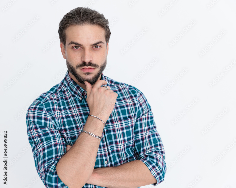 thoughtful young man in plaid shirt touching chin and thinking thoughtful young man in plaid shirt touching chin and thinking