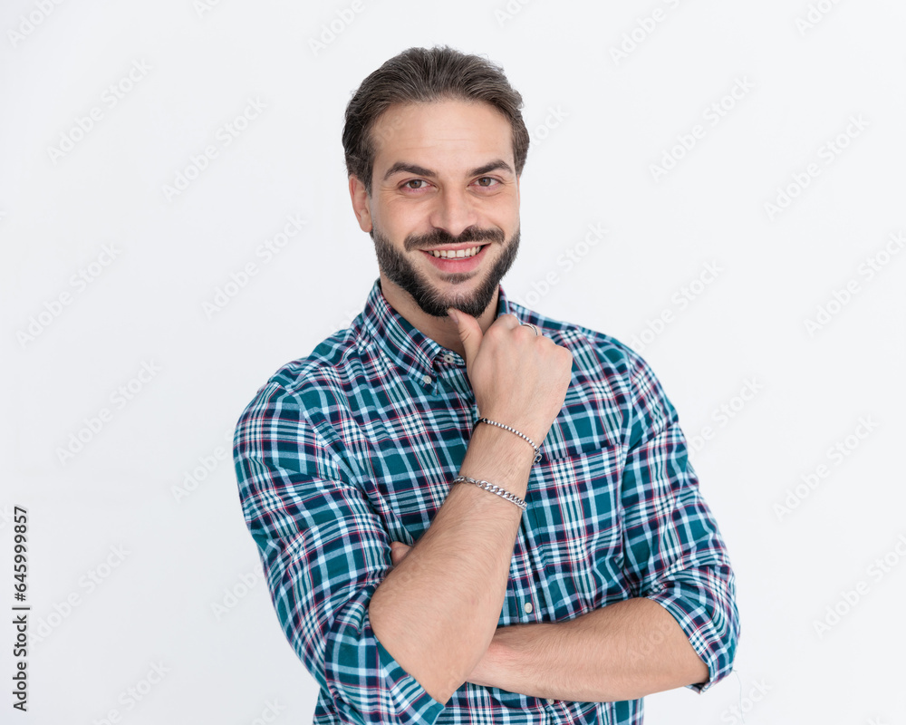 happy young man in plaid shirt folding arms and touching chin happy young man in plaid shirt folding arms and touching chin