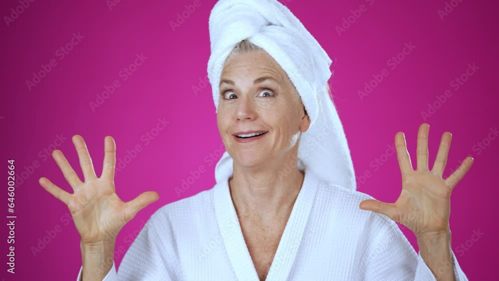 Smart pretty elderly blonde woman lady 50s years old wears white robe and towel on head, show mind explosion isolated on solid pink background studio portrait. People emotions lifestyle concept Smart pretty elderly blonde woman lady 50s years old wears white robe and towel on head, show mind explosion isolated on solid pink background studio portrait. People emotions lifestyle concept
