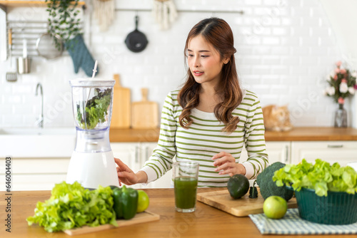 Portrait of beauty healthy asian woman making green vegetables detox cleanse and green fruit smoothie with blender.young girl drinking glass of smoothie  fiber  chlorophyll in kitchen.Diet  healthy
