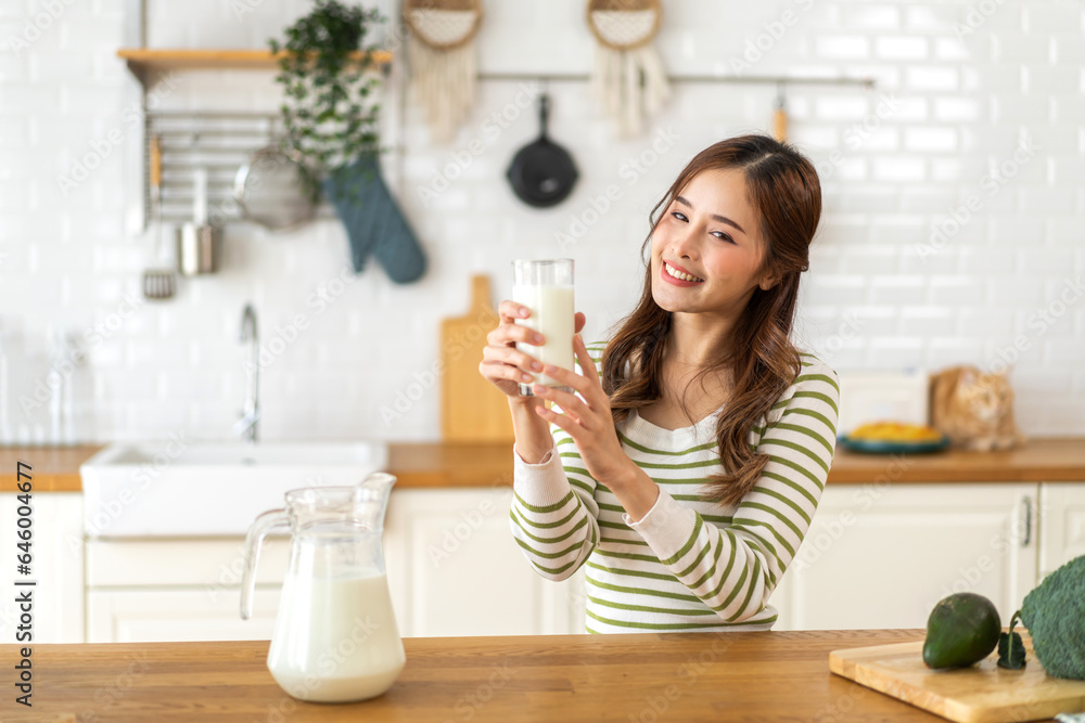 Portrait of beauty healthy asian woman smiling and having protein breakfast drinking and hold glasses of milk of fresh milk, nutrition,calcium and vitamin,dairy product in kitchen at home.Diet concept Portrait of beauty healthy asian woman smiling and having protein breakfast drinking and hold glasses of milk of fresh milk, nutrition,calcium and vitamin,dairy product in kitchen at home.Diet concept