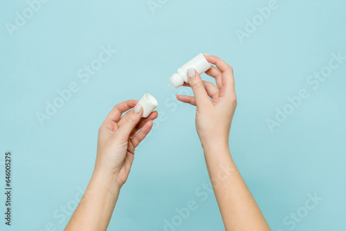 Bottle of eye drops (nasal spray) in woman's hand. Copy space