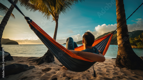 Happy man lies in a hammock against a backdrop of palm trees and the sea during a vacation