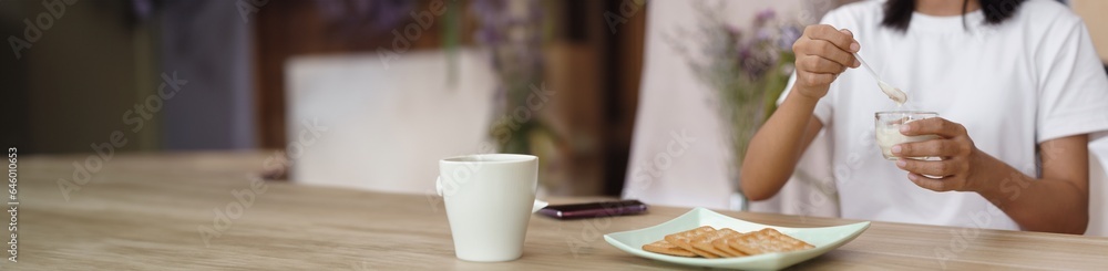 Home relaxation concept, Young woman eating yogurt and crackers for snack while relaxation at home Home relaxation concept, Young woman eating yogurt and crackers for snack while relaxation at home