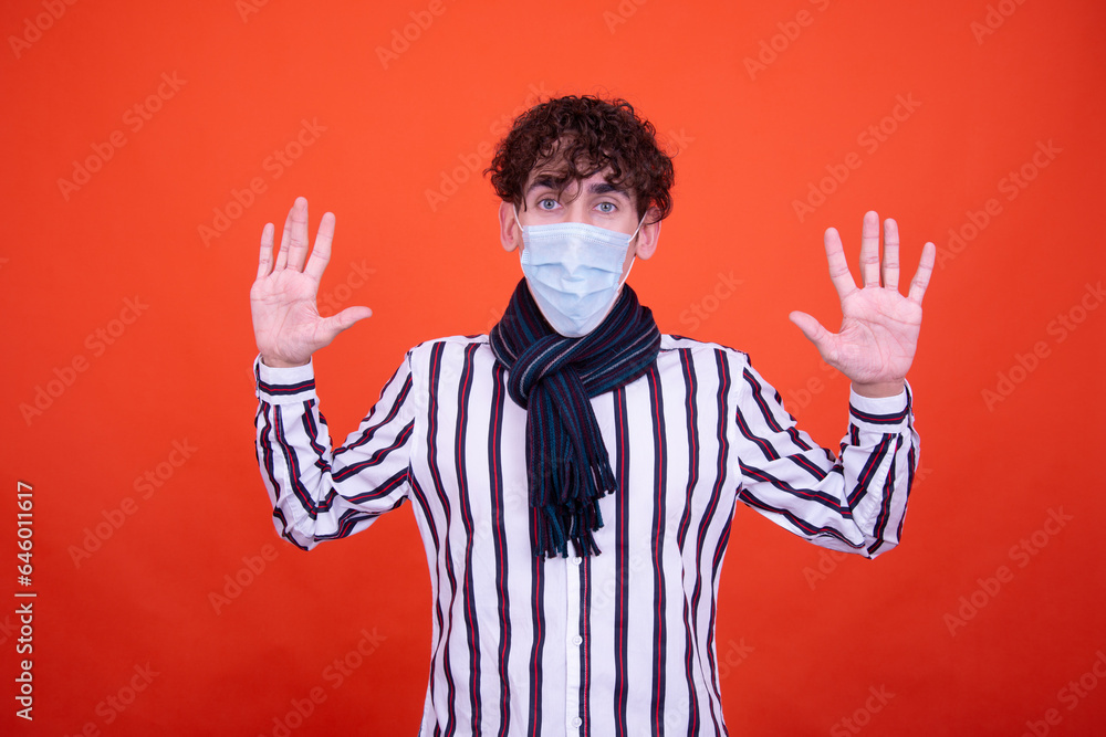 Funny curly guy posing in the studio on an orange background. Illness and protection against colds. Funny curly guy posing in the studio on an orange background. Illness and protection against colds.