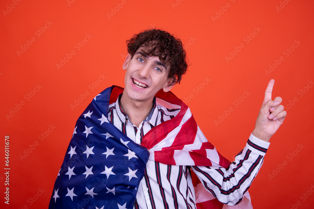 Funny curly guy posing in the studio on an orange background with the national flag. Funny curly guy posing in the studio on an orange background with the national flag.