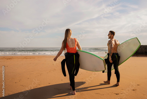 Watersports Concept. Young Couple With Surfboards Going Into The Ocean