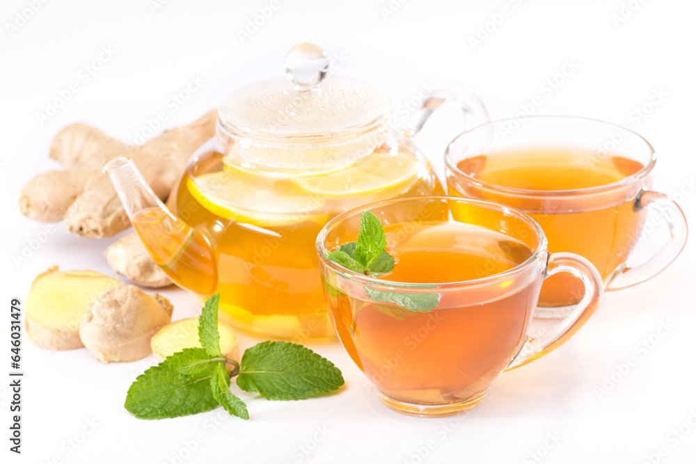 Hot beverage concept for health upkeep. Side view photo of a cup of tea, teapot, ginger root and mint leaves on a white background Hot beverage concept for health upkeep. Side view photo of a cup of tea, teapot, ginger root and mint leaves on a white background