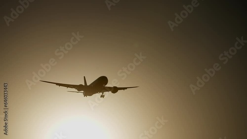 A passenger plane coming in for landing is flying with its landing gear released against the backdrop of a picturesque orange sunset. The concept of travel, tourism, flights and transport.