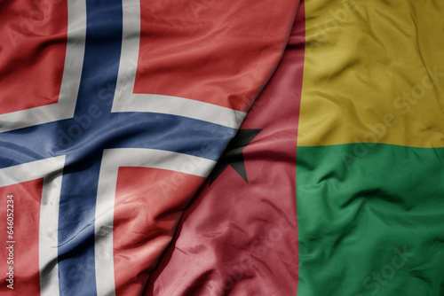 big waving national colorful flag of norway and national flag of guinea bissau .