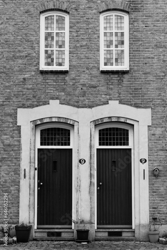 Black and white version of a historic facade with twin doors and windows entirely in symmetry.