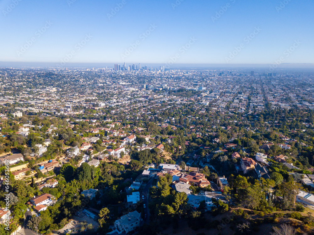 Aerial view of the Los Feliz neighborhood with large houses in the hills and downtown Los angeles skyline in the background.