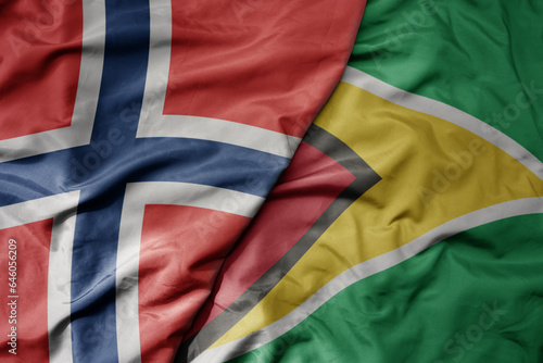big waving national colorful flag of norway and national flag of guyana .