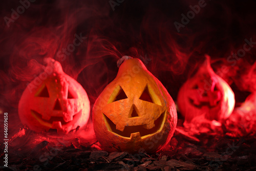 Three pumpkins with red light and smoke