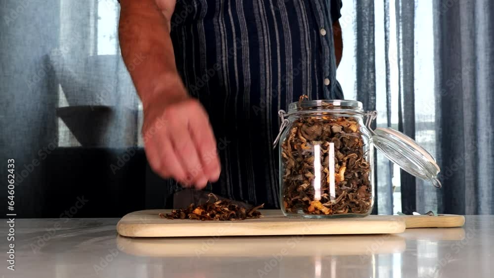 Stockholm, Sweden A man places wilderness-picked, foraged, and dried chanterelle mushrooms into a jar on a table. Stockholm, Sweden A man places wilderness-picked, foraged, and dried chanterelle mushrooms into a jar on a table.