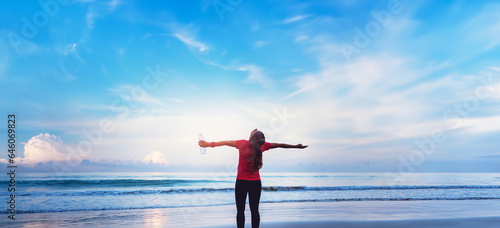 Asian women jogging workout on the beach in the morning. Relax with the sea walk and drinking water from the plastic bottles