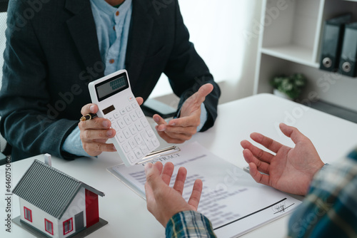 A real estate agent is talking with a client about buying a home or getting home insurance. Real estate agent buys, sells a house, agrees to buy a house.