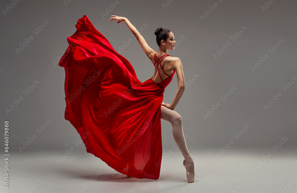Ballerina. Young graceful woman ballet dancer, dressed in professional outfit, shoes and red weightless skirt is demonstrating dancing skill. Beauty of classic ballet. - obrazy, fototapety, plakaty 