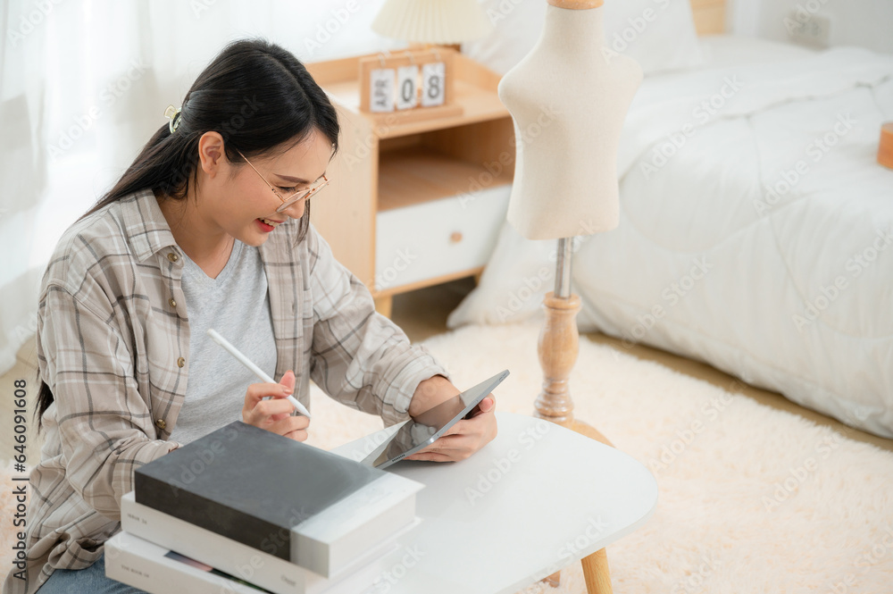 A women working freelance relaxed lifestyle at work in the living room of her home, using the tablet for creative or design work. Asian woman using tablet to surf the internet and do work