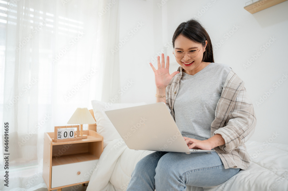 Asian girl freelance translator who is happy to work She is working on a laptop. In her bed chatting remotely online on her bed laptop. Asian girl freelance translator who is happy to work She is working on a laptop. In her bed chatting remotely online on her bed laptop.