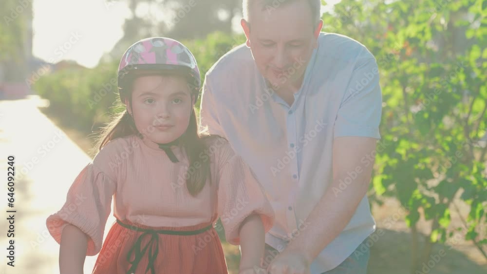 Child cyclist with Father, nature. Happy family, little girl in helmet