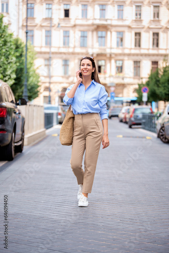 Brunette haired woman walking on the street and using mobile phone © gzorgz