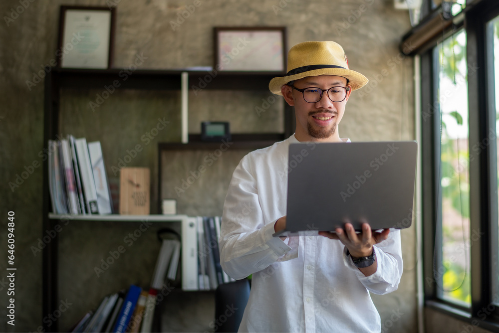 Businessman in casual clothes standing working with laptop in his home office Businessman in casual clothes standing working with laptop in his home office