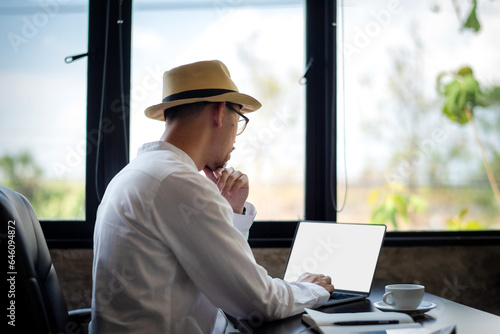 Businessman in casual clothes Focus on working in front of laptop at home office. Working on the white screen laptop. © Wasana