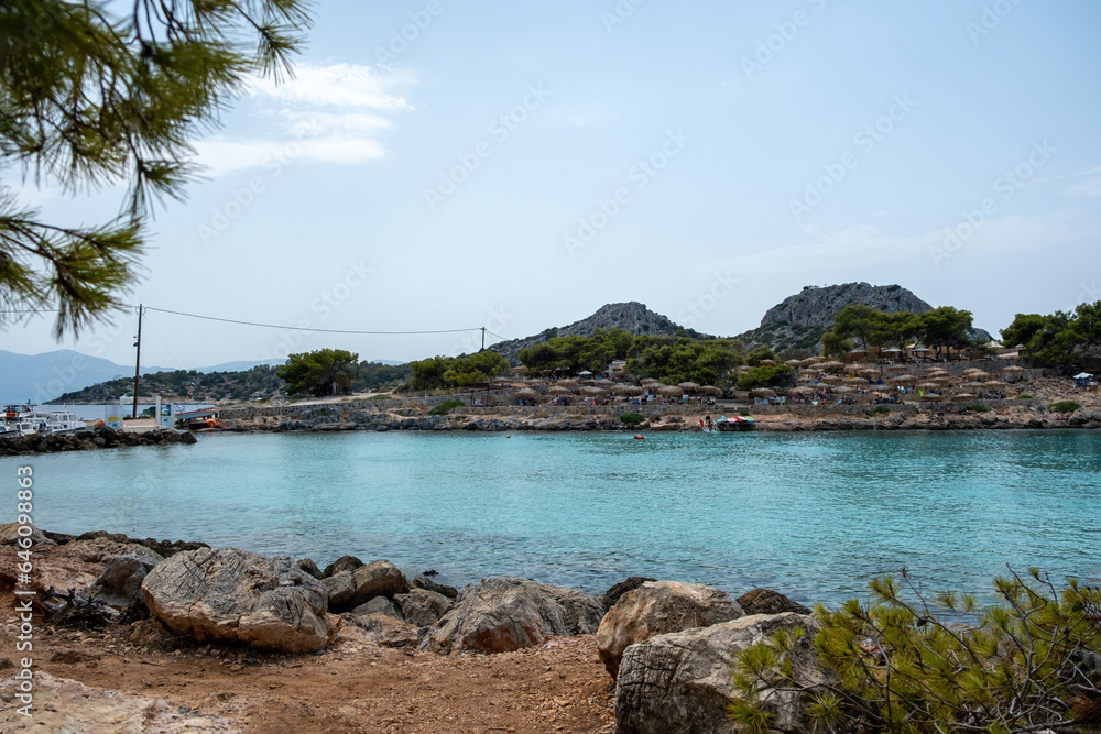 Aponisos beach Agistri island Greece. Rocky beach with pine tree, clear sea, moored boat, blue sky. Aponisos beach Agistri island Greece. Rocky beach with pine tree, clear sea, moored boat, blue sky.