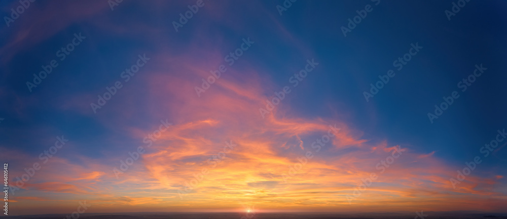 Fire on the sky: From high above, far sunset and orange and red colored streakes of cirrus clouds on deep blue evening sky.  Ideal for sky replacement projects, no obstacles in the front.