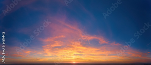Fire on the sky: From high above, far sunset and orange and red colored streakes of cirrus clouds on deep blue evening sky.  Ideal for sky replacement projects, no obstacles in the front.