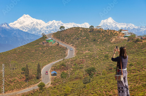 Young female tourist takes photographs of the scenic landscape with the majestic Kanchenjunga Himalaya range at Tinchuley,a popular hill station near Darjeeling, India photo