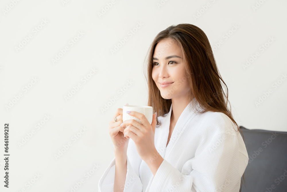 Beautiful Asian woman in white robe holding cup of coffee Beautiful Asian woman in white robe holding cup of coffee