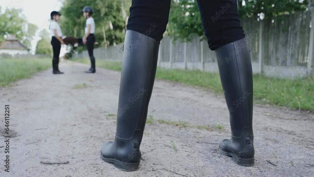 Hobbyhorsing. Girls jockeys communicate with each other, one stands aside and watches. A close-up of legs in boots, in the distance a blurred background of girls talking to each other. Hobbyhorsing. Girls jockeys communicate with each other, one stands aside and watches. A close-up of legs in boots, in the distance a blurred background of girls talking to each other.