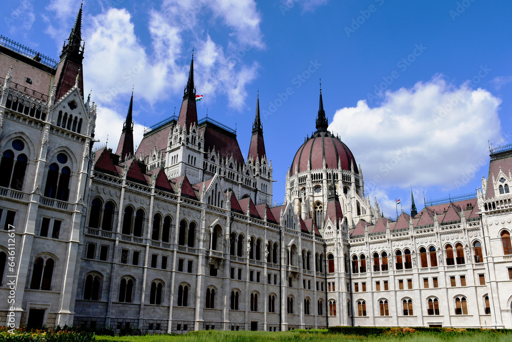 exterior closeup detail of the Hungarian Parliament in Budapest. stone building in neo gothic style. popular travel destination and landmark building. European tourism. dynamic blue sky. white clouds