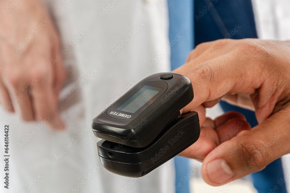 Man using a pulse oximeter in a finger Man using a pulse oximeter in a finger