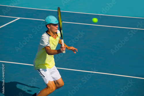 young man plays tennis on a blue hard-coated court © Павел Мещеряков