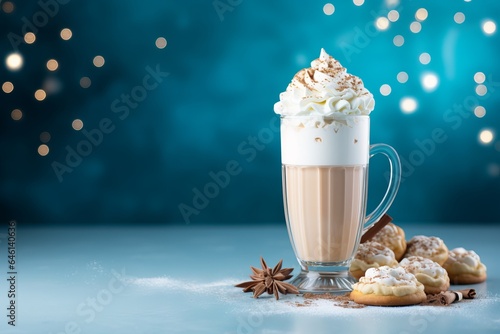 a tall glass with warm coffee drink with cinnamon, whipped milk foam or cream and caramel on a kitchen table and christmas ornaments, lights and decoration.