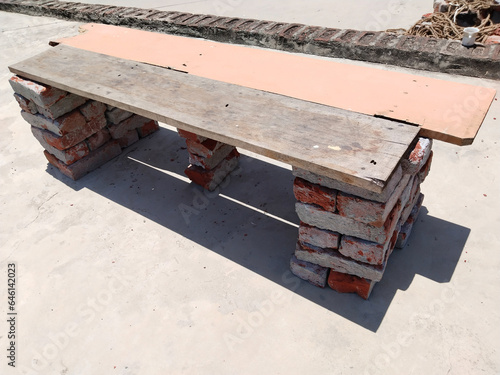 wooden plank on bricks for sitting people on this plank. bench used in rural area's shops schools and houses. Wooden bench made of two pieces of tree trunks and planks. resting place 