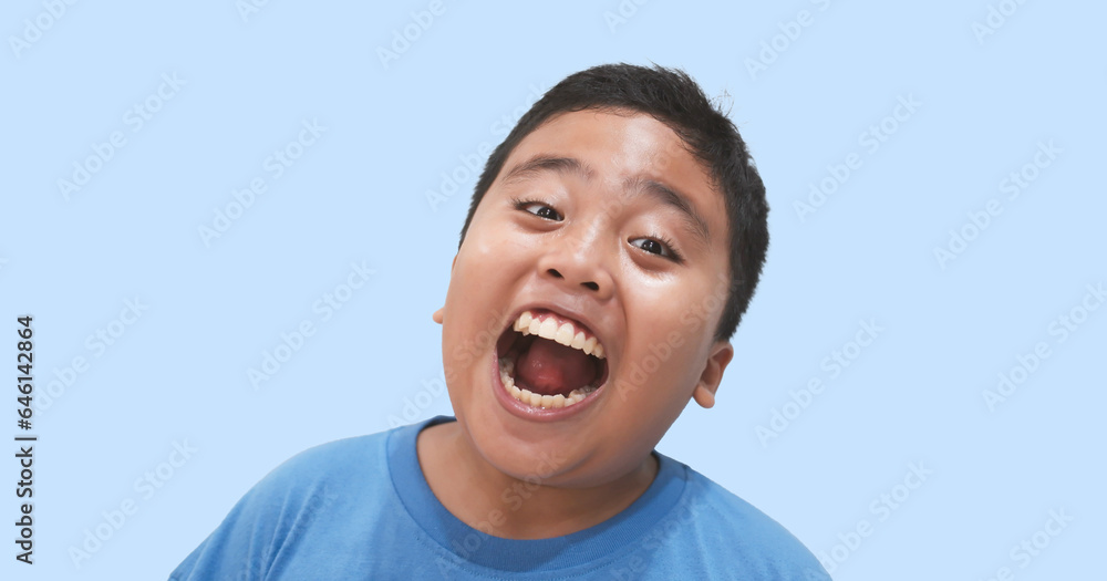 close-up portrait, a joyful and cheerful young boy is seen with a happy expression, mouth wide open, set against an isolated light blue background close-up portrait, a joyful and cheerful young boy is seen with a happy expression, mouth wide open, set against an isolated light blue background