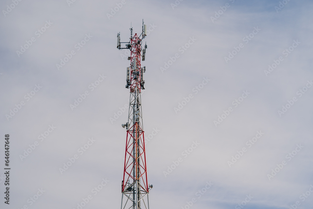 Radio and telecommunication tower with antennas and bright red and white colouring of metal