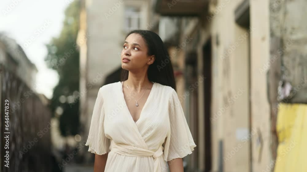 Charming young woman walking down the street and looking around outdoors Smiling relaxed female walking on the city centre enjoying beautiful day Natural beauty lady in write dress alone Charming young woman walking down the street and looking around outdoors Smiling relaxed female walking on the city centre enjoying beautiful day Natural beauty lady in write dress alone