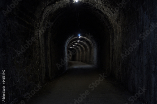 stone tunnel dark wet old curved stone illuminated with dirt floor in horizontal