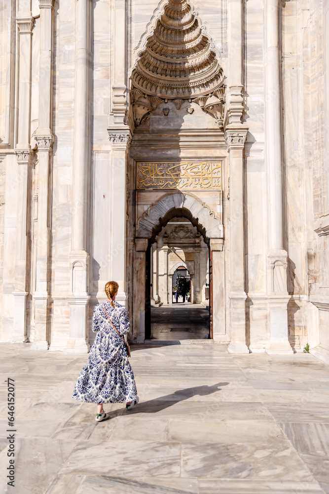Istanbul, Turkey - July 22,2023: A blonde woman walking amongst the architecture of the Nuruosmaniye Mosque in Istanbul
