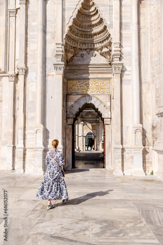 Istanbul, Turkey - July 22,2023: A blonde woman walking amongst the architecture of the Nuruosmaniye Mosque in Istanbul  © Torval Mork