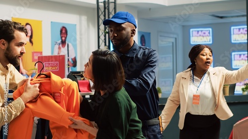 People into shopping madness during black friday sales, arguing over clothes with big discount. Angry customers pulling merchandise and being obsessed over promotional clearance items.