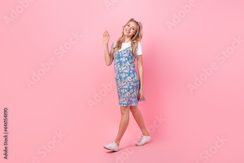 Full body profile portrait of lovely positive lady walking arm palm waving hi isolated on pink color background