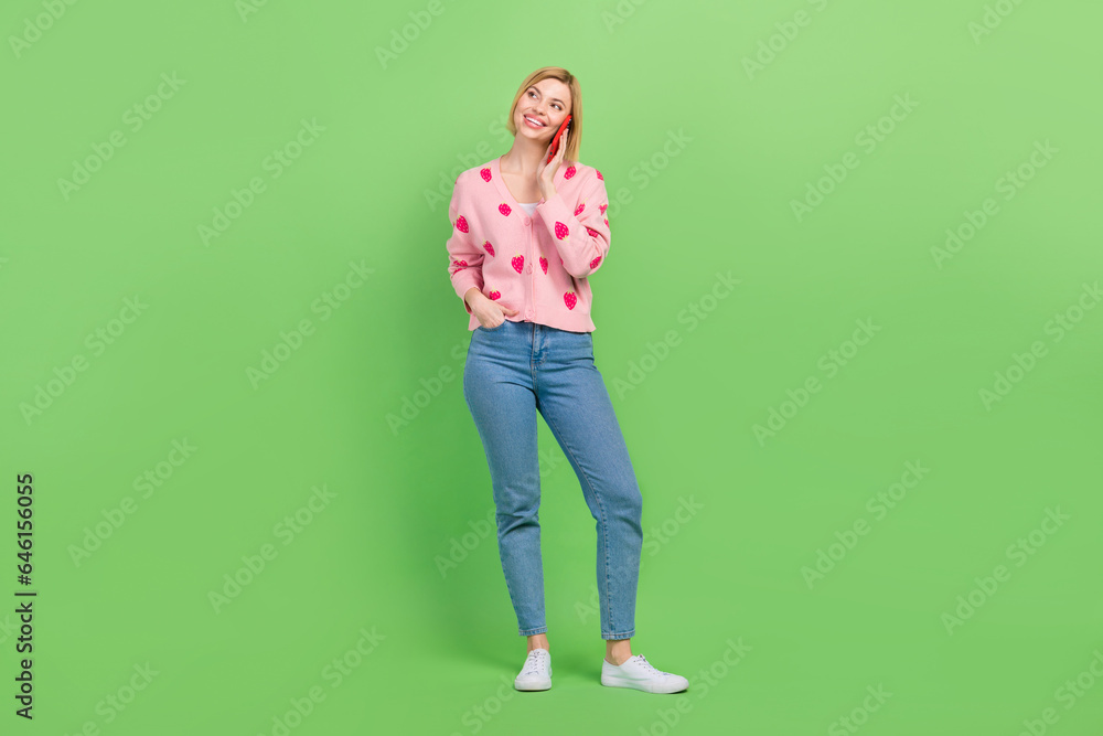 Full size photo of attractive woman empty space talk phone dressed stylish pink strawberry print clothes isolated on green color background Full size photo of attractive woman empty space talk phone dressed stylish pink strawberry print clothes isolated on green color background