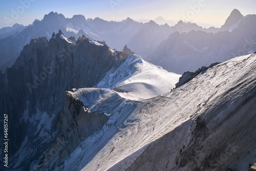 The steep and extremely exposed ice ridge to descend to the glacier below the Aiguille du Midi cable car station. Climbers on the ice ridge. Chamonix-Mont-Blanc. photo